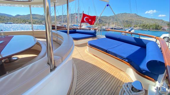 The spacious sun deck of the Gulet Sahinoğlu offers comfortable seating with blue cushions.